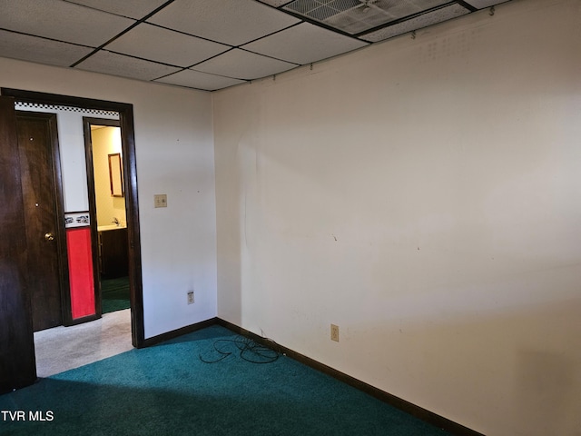 spare room with a paneled ceiling, carpet, and baseboards