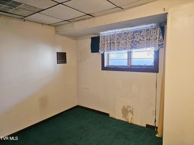 empty room featuring a paneled ceiling, baseboards, and dark colored carpet