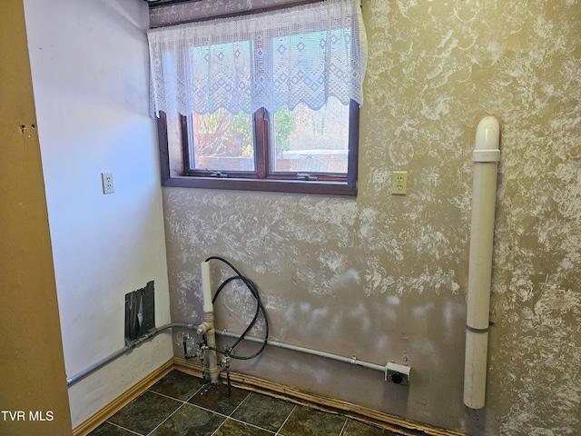 washroom with wallpapered walls, baseboards, laundry area, and dark tile patterned floors