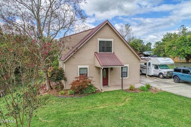 view of front of property featuring metal roof, driveway, and a front lawn