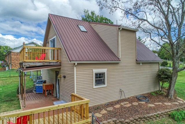 back of house featuring metal roof, a yard, and a deck