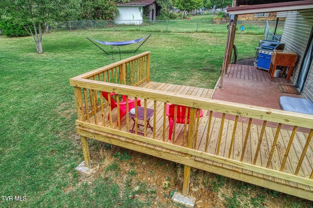 wooden terrace featuring a fenced backyard, a lawn, and area for grilling