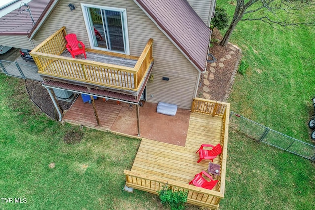 rear view of property with fence, a wooden deck, and a lawn