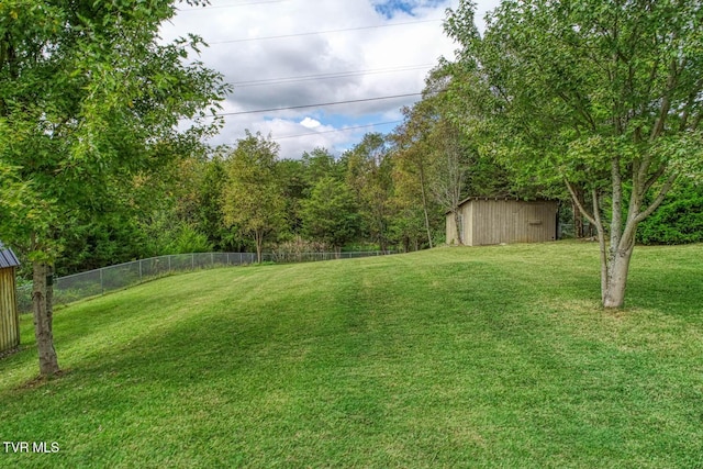 view of yard featuring an outbuilding, a shed, and fence