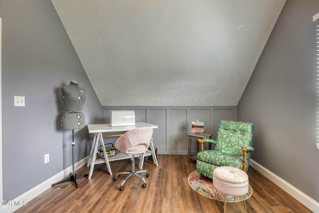 office area featuring lofted ceiling, dark wood-style flooring, a decorative wall, and baseboards