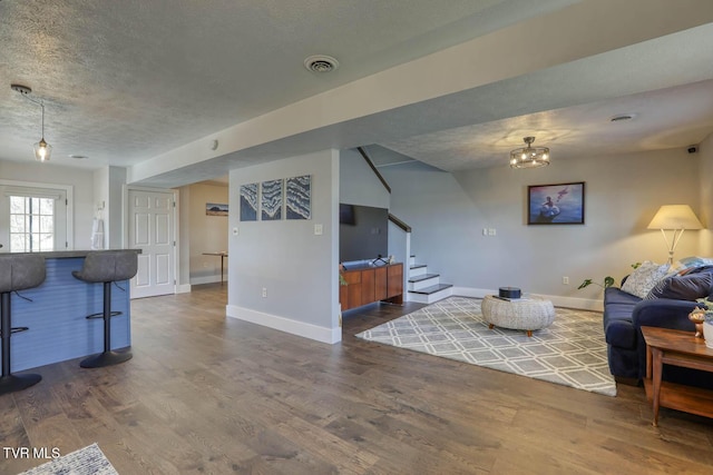 living area featuring stairs, visible vents, dark wood finished floors, and a textured ceiling