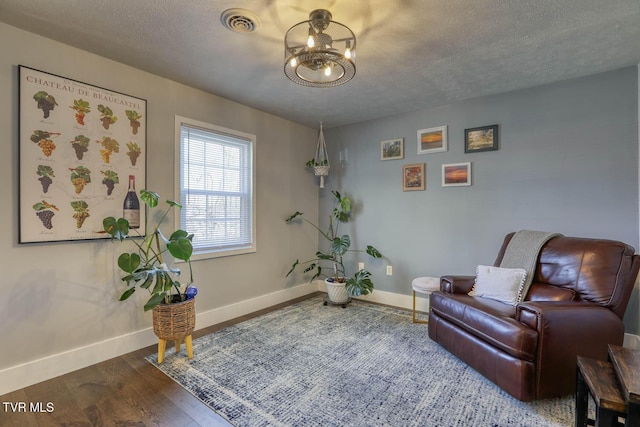 sitting room featuring a textured ceiling, dark wood finished floors, visible vents, and baseboards