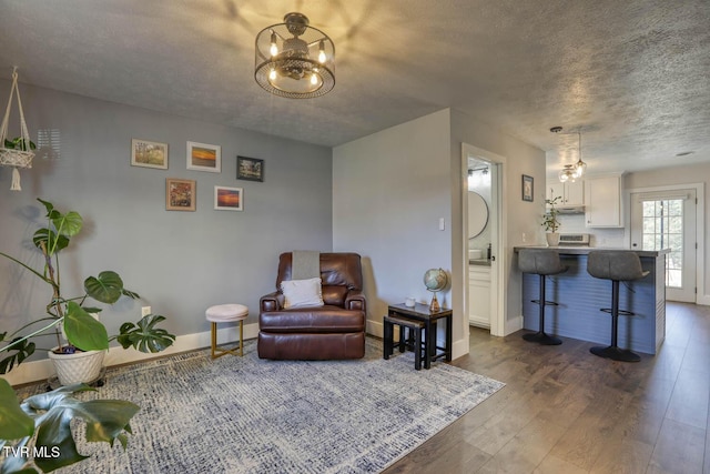 interior space with dark wood-type flooring, a textured ceiling, baseboards, and an inviting chandelier