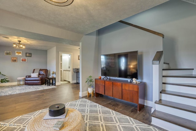 living room featuring dark wood finished floors, stairway, a textured ceiling, a chandelier, and baseboards