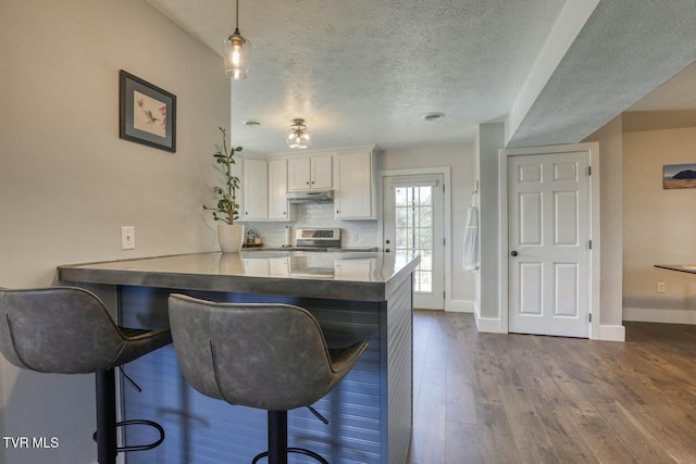 kitchen featuring a peninsula, a breakfast bar area, and white cabinets