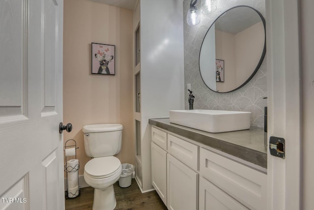 half bathroom with baseboards, vanity, toilet, and wood finished floors