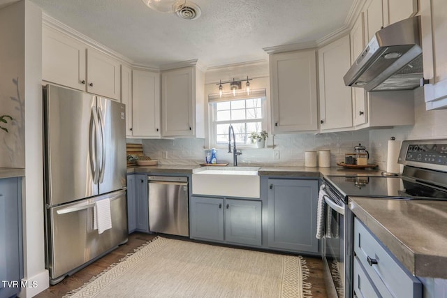 kitchen with stainless steel appliances, dark countertops, and under cabinet range hood