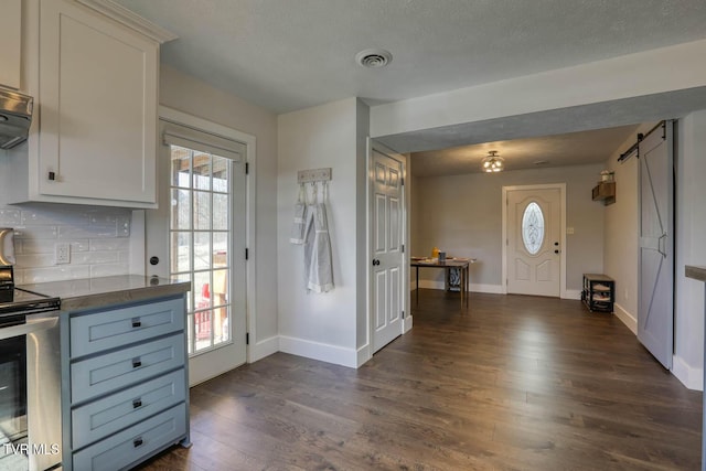 kitchen with dark countertops, white cabinets, stainless steel electric range oven, and a barn door