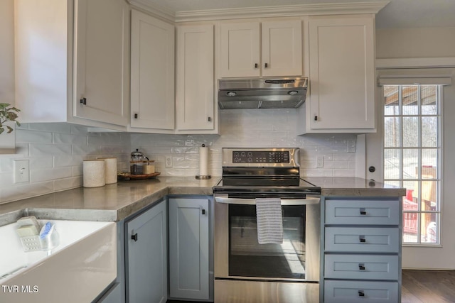 kitchen with white cabinets, decorative backsplash, dark countertops, under cabinet range hood, and stainless steel range with electric stovetop