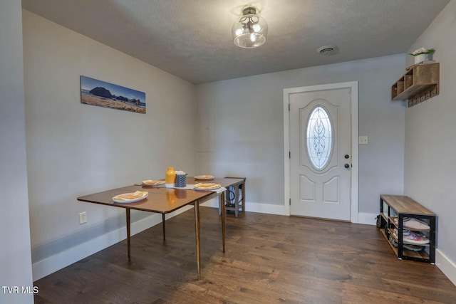 entrance foyer with dark wood-style floors, a textured ceiling, visible vents, and baseboards