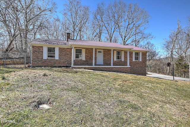 ranch-style home featuring a front yard, fence, metal roof, and brick siding