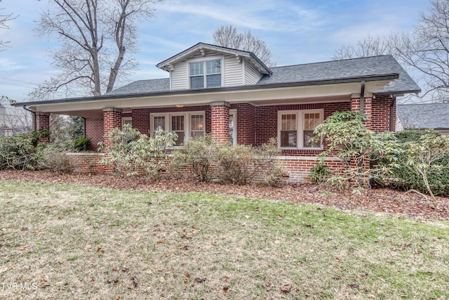 view of front facade featuring brick siding, a front lawn, and roof with shingles