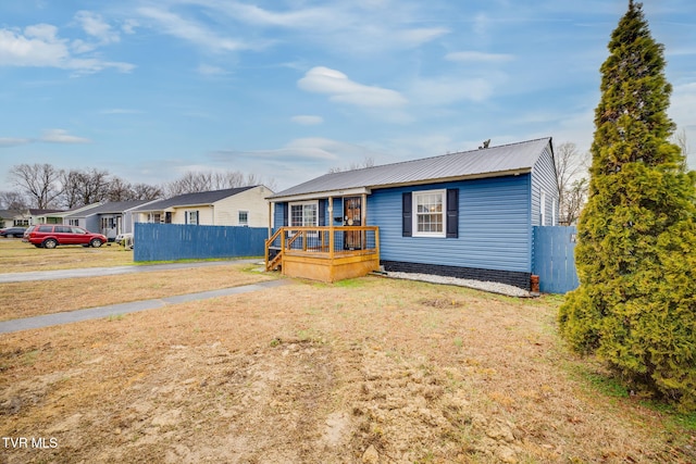 view of front facade with metal roof, fence, and a front lawn