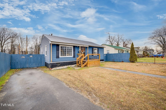 view of front of house with driveway, metal roof, crawl space, fence, and a front yard