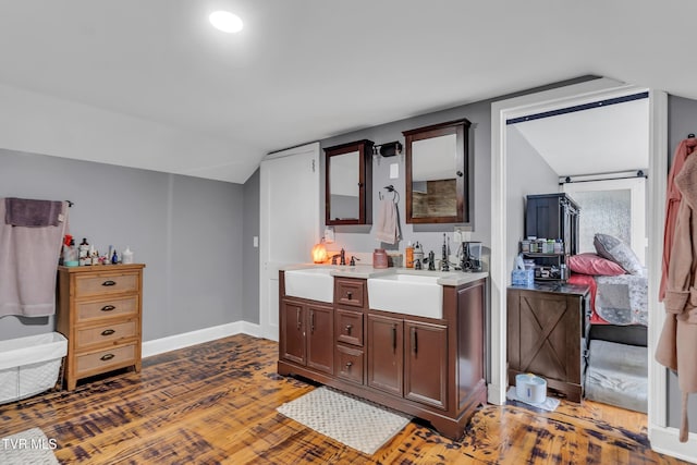 bathroom featuring lofted ceiling, double vanity, a sink, and wood finished floors