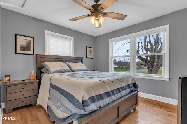 bedroom with light wood-type flooring, ceiling fan, and baseboards