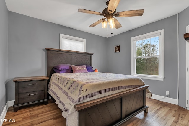 bedroom with ceiling fan, light wood finished floors, and baseboards