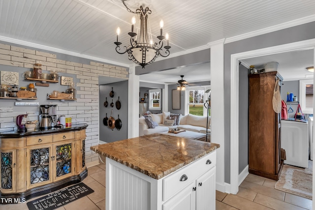 kitchen featuring crown molding, light tile patterned floors, hanging light fixtures, white cabinetry, and brick wall