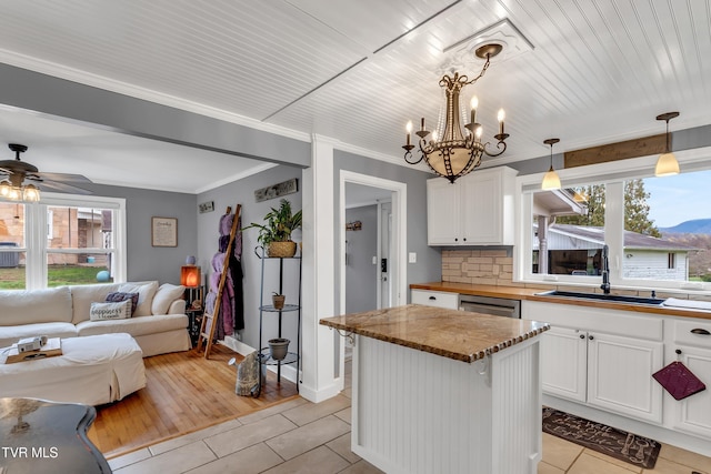 kitchen with light tile patterned flooring, a sink, white cabinets, dishwasher, and pendant lighting