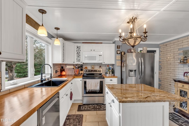 kitchen featuring white cabinetry, appliances with stainless steel finishes, pendant lighting, and a sink