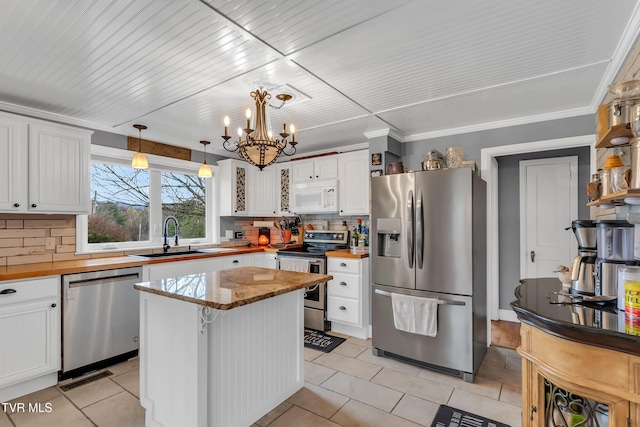 kitchen featuring a center island, hanging light fixtures, stainless steel appliances, white cabinetry, and a sink