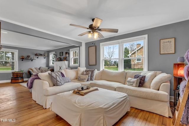 living room with ornamental molding, light wood-style floors, baseboards, and ceiling fan