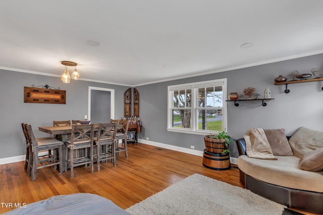 dining area featuring baseboards, ornamental molding, and wood finished floors