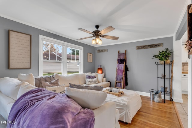 living area with light wood-style floors, crown molding, baseboards, and a ceiling fan