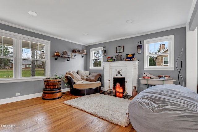 bedroom featuring baseboards, a brick fireplace, wood finished floors, and crown molding