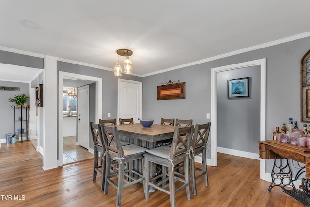 dining room with ornamental molding, light wood-style flooring, and baseboards