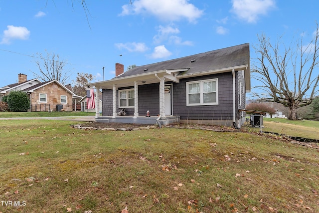 bungalow with covered porch, a front lawn, a chimney, and central AC unit