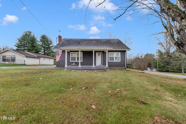 bungalow-style home with covered porch, a chimney, and a front yard