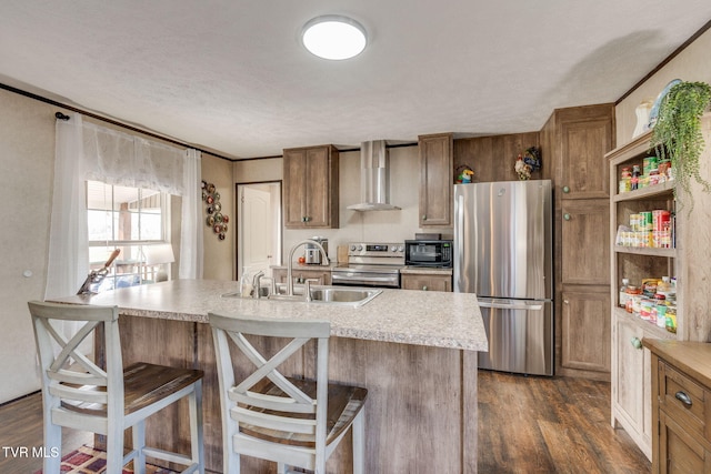 kitchen featuring wall chimney range hood, dark wood finished floors, stainless steel appliances, and light countertops