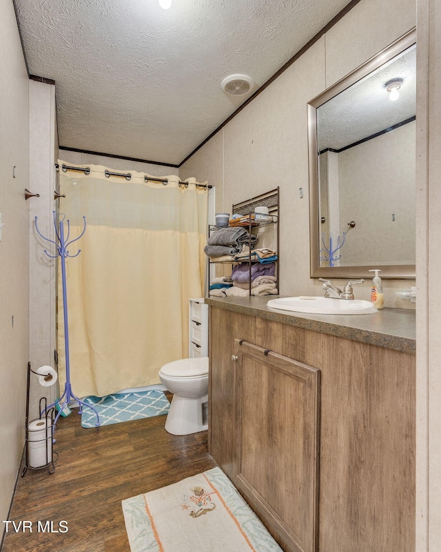 full bath with toilet, a textured ceiling, visible vents, and wood finished floors