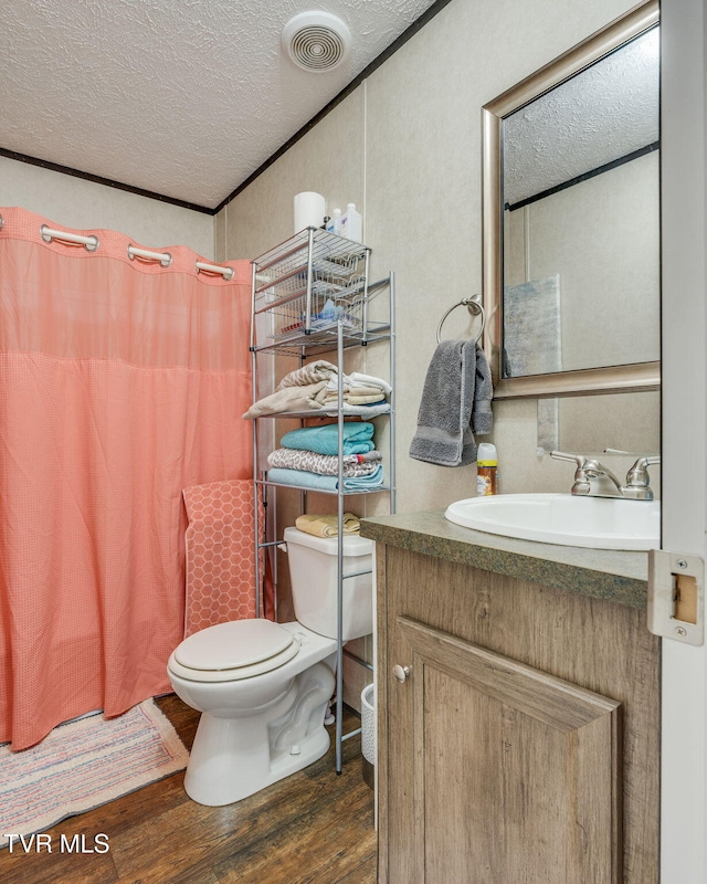 full bathroom featuring curtained shower, toilet, vanity, a textured ceiling, and wood finished floors