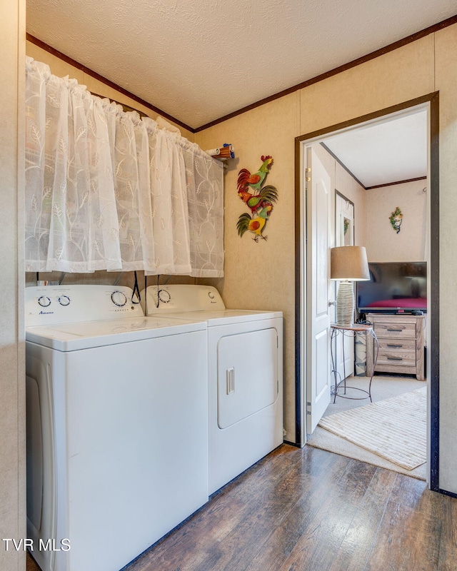 laundry area featuring washing machine and dryer, laundry area, crown molding, and hardwood / wood-style flooring