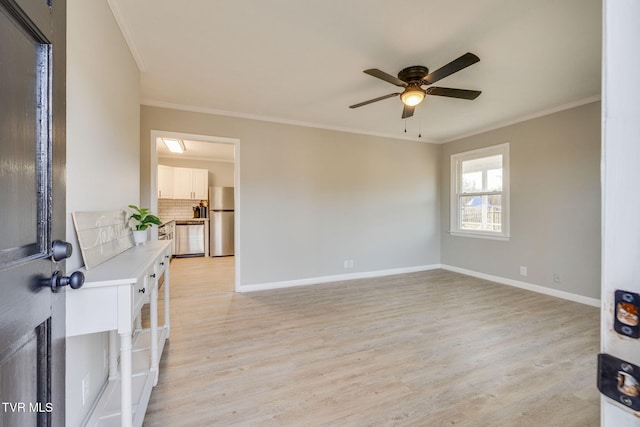 interior space featuring light wood-style floors, ceiling fan, baseboards, and ornamental molding