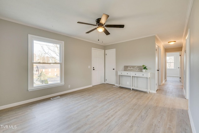 interior space featuring a ceiling fan, baseboards, visible vents, light wood finished floors, and crown molding