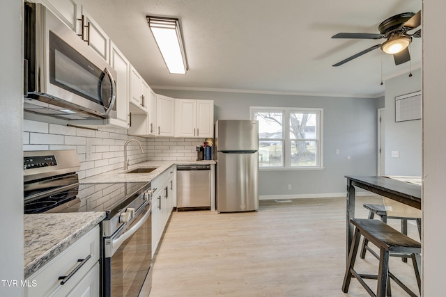 kitchen featuring decorative backsplash, appliances with stainless steel finishes, light stone countertops, crown molding, and white cabinetry