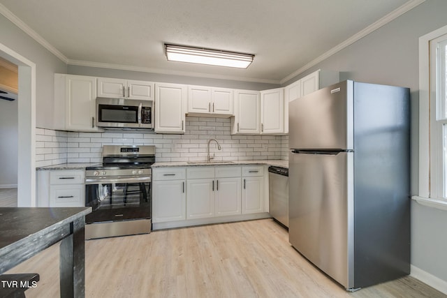 kitchen featuring stainless steel appliances, a sink, light wood-style flooring, and white cabinets