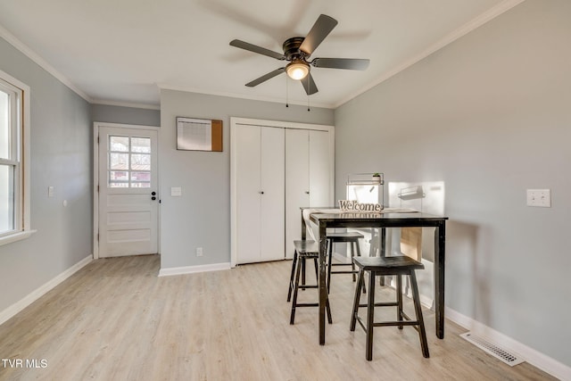 dining area featuring light wood-type flooring, baseboards, visible vents, and ornamental molding