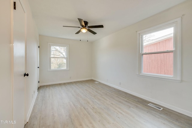 spare room featuring baseboards, a ceiling fan, visible vents, and light wood-style floors