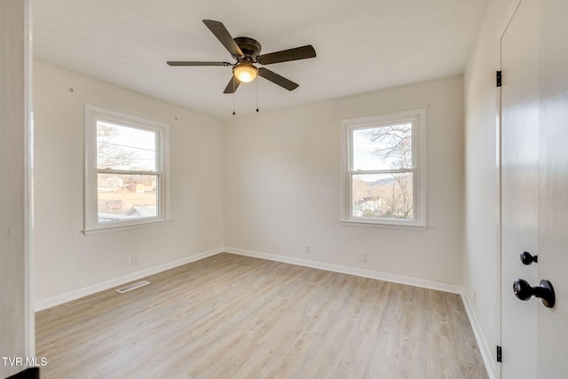 spare room featuring plenty of natural light, visible vents, light wood-style flooring, and baseboards