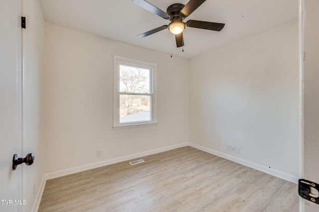 spare room with light wood-type flooring, visible vents, ceiling fan, and baseboards