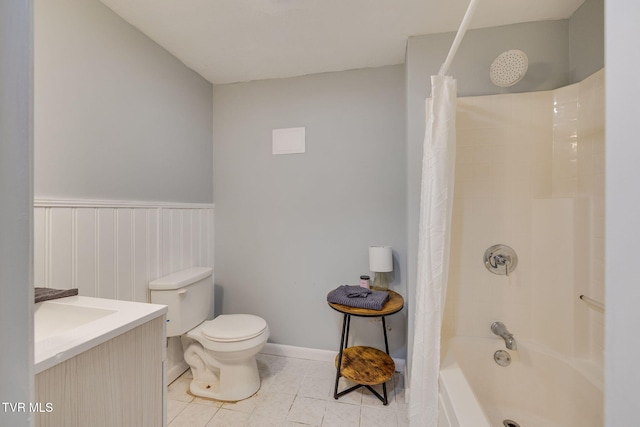 full bathroom with tile patterned flooring, toilet, shower / tub combo, vanity, and wainscoting